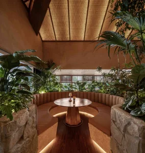 Dining area with a round table and chairs, surrounded by potted plants, in a modern and stylish restaurant setting