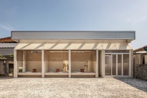 A modern outdoor dining space with a concrete patio, a dining table, and chairs, filled with natural light