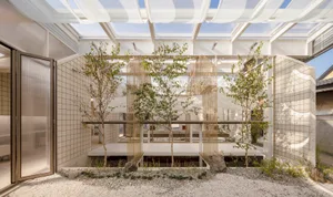 A cozy indoor space with a mix of living and garden areas, featuring potted plants, a dining table, and a couch, with a blend of natural and modern elements