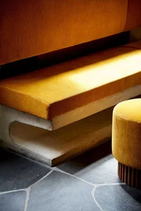 A living area with two leather couches on a stone floor, well-lit with natural or artificial light