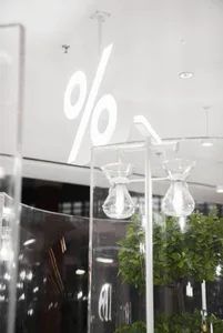 A modern interior design showroom featuring three glass vases on clear stands in front of a white wall with a large number 90, creating a minimalist and elegant atmosphere