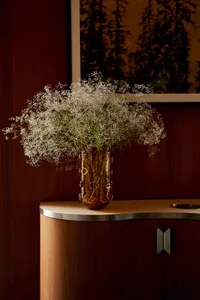 A vase with white flowers on a wooden table in a cozy living area