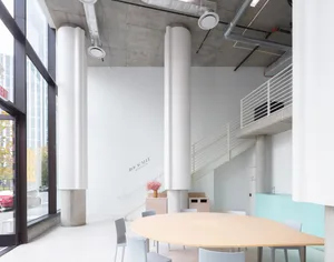 Empty modern room with a large wooden table and chairs, concrete ceiling and walls, and a clean and minimalistic atmosphere