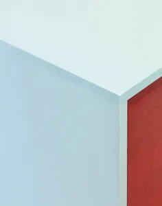 A striking geometric art installation with a red wooden section and a white concrete section, creating a visually appealing contrast