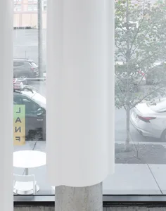 窗前白色柱子的現代辦公空間，周圍停有車輛與座椅，傳達寧靜有序的氛圍