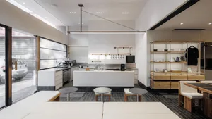 Modern open kitchen with white walls, a dining table, chairs, and various appliances