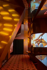 Modern living space with a dining table, chairs, and two TV screens mounted on the wall, in a stylish and social atmosphere