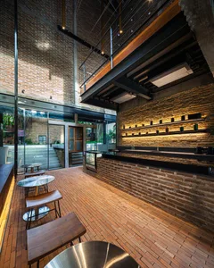 Warm and inviting bar area with a brick wall, wooden floors, and a countertop, featuring chairs and a comfortable atmosphere