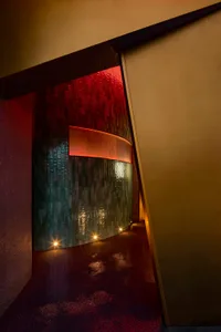 A bathroom with a red wall and a green wall, featuring a red doorway and tile-covered walls in a modern space