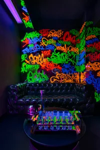 A modern living room with graffiti artwork, two couches, a chair, and a table with a vase and cup, creating a unique urban atmosphere