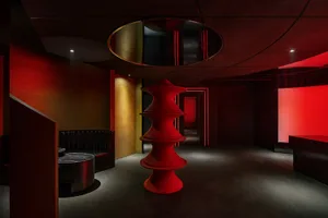 A darkened room with a red spiral staircase, two benches, and a mysterious atmosphere