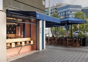 Outdoor cafe with a mix of wood and metal elements, umbrellas, and seating areas for patrons