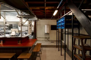 Industrial kitchen with a dining table and chairs, two refrigerators, and a functional atmosphere
