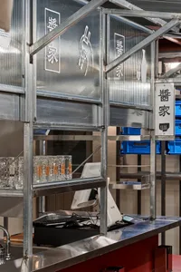Industrial storage space with a metal wall featuring signs, glasses, and cups, with a utilitarian atmosphere and numerous items on display