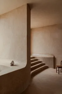 Empty modern room with concrete walls, a staircase, and two chairs, dimly lit