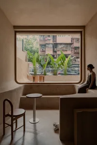 Cozy living space with two benches, a dining table, potted plants, and a chair, creating a warm and inviting atmosphere