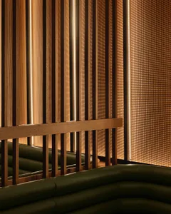 A modern living space with wooden walls and a green couch, featuring two couches and a warm inviting atmosphere