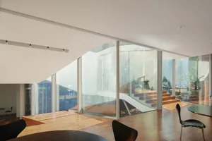 Open living area with glass walls, natural light, two chairs, and a dining table