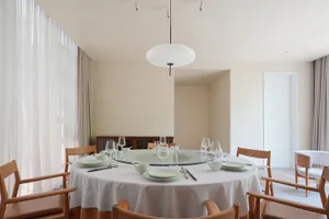 A dining room with a round table set for a meal, surrounded by chairs, in a clean and organized space with a sense of elegance