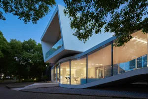 Modern building with curved design, large windows, and natural light, featuring glass and concrete materials