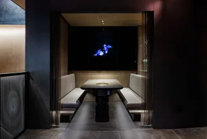 Cozy cafe interior with two couches, a wooden dining table, chairs, and a TV mounted on the wall