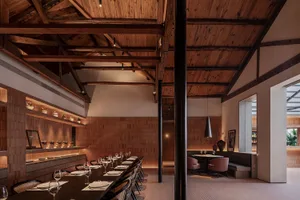 Empty restaurant interior with wooden floors and walls, featuring dining tables and chairs in a welcoming atmosphere