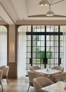 Bright dining space with a large window, modern chairs, a dining table, and a potted plant