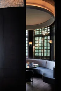A black and white interior space with two couches, a dining table, chairs, and a large window allowing natural light