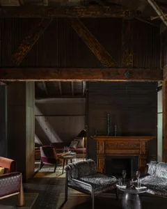 Inviting living area with a fireplace, couches, chairs, and a dining table, featuring various decorative elements and a warm atmosphere