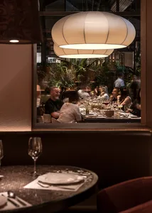 A lively restaurant scene with multiple dining tables, chairs, and wine glasses, set in a comfortable and inviting atmosphere