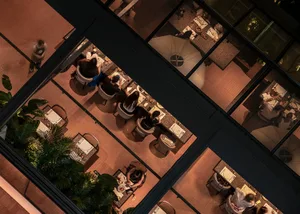 Inviting restaurant interior with wooden tables, chairs, and potted plants, featuring a warm and comfortable atmosphere