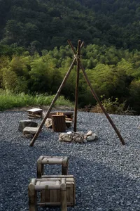 A cozy outdoor camping area with a wooden structure, fire pit, and two benches, perfect for colder months