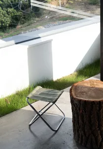 A well-lit outdoor patio with a green chair and a tree stump, surrounded by a relaxing atmosphere