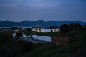 山坡上俯瞰湖景的現代住宅，設有寬敞露台與多把戶外座椅