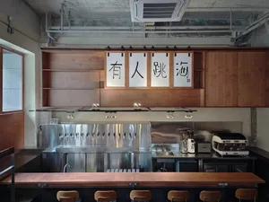 A well-lit Asian restaurant interior with a wooden theme, featuring a bar area with chairs and signs, and a welcoming atmosphere