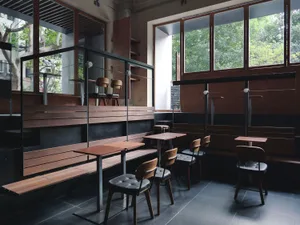 Modern restaurant interior with wooden floors, tables, and chairs, creating a warm and inviting atmosphere