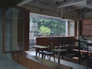 Warm and inviting restaurant interior with wooden floors and walls, modern metal-legged tables, and comfortable seating