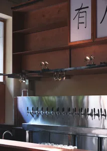 A modern bar area with stainless steel fixtures and a large number of beer taps mounted on the wall in a lively social environment