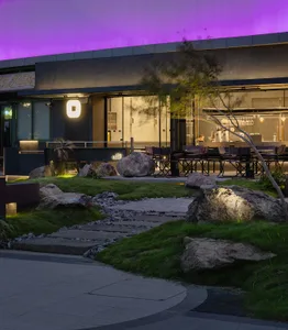 Outdoor restaurant area with patio seating, benches, and nearby trees creating a natural ambiance