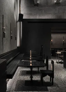 Empty modern restaurant with black walls, dining tables, and candles creating a warm atmosphere