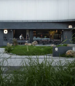 A relaxed outdoor restaurant patio with multiple dining tables and chairs, surrounded by a natural setting, with people enjoying their meals