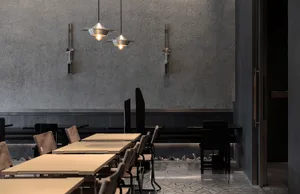 A modern restaurant with several dining tables and chairs, featuring a clean and well-organized atmosphere with soft and warm lighting