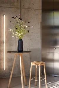 A cozy living space with a wooden table, two chairs, and a black vase filled with flowers, creating a warm and inviting atmosphere
