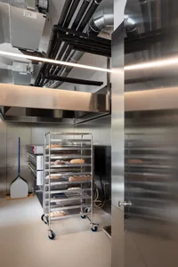 Industrial kitchen with a large metal rack filled with various types of bread, showcasing a diverse selection of baked goods in a professional environment