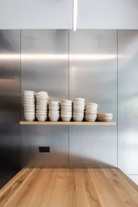 A modern kitchen with a metal wall displaying a collection of plates in various sizes and shapes, arranged in an organized and visually appealing manner