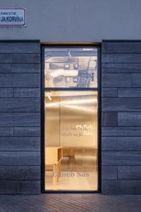 A bright and airy interior space with glass walls, a modern chair, and two benches, flooded with natural light from a large window