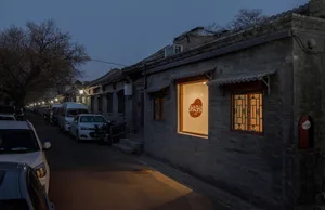 夜晚熱鬧的亞洲城市街道，伴有小型磚造建築、汽車，以及停靠路邊的卡車