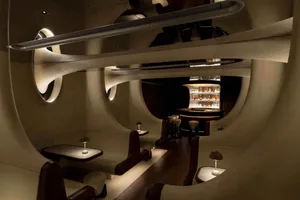 A social bar area with a wooden bar, chairs, and bottles displayed on the counter, creating an inviting atmosphere for gatherings and relaxation