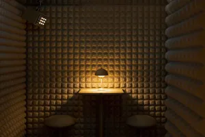 Cozy dining space with a small table, two stools, two chairs, and a lamp, featuring a unique patterned wall