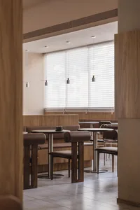 Empty restaurant interior with wooden walls, tables, and chairs, featuring a calm and inviting atmosphere with dim lighting